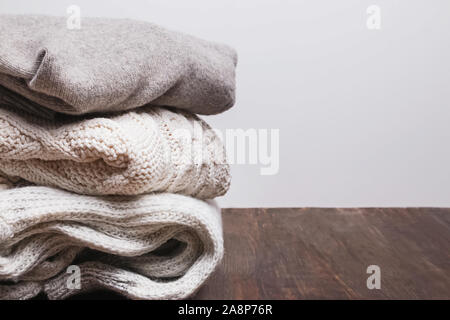 Pile of warm knitted sweaters on the wooden table Stock Photo