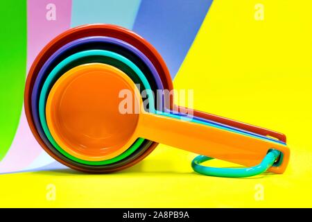 Color pop still life of measuring spoons on a bright background of different colors, yellow the most prominent. Stock Photo