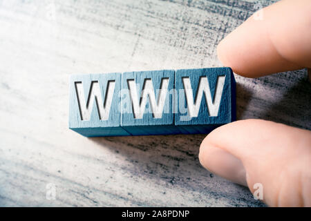 The Word WWW On Wooden Blocks And Arranged By Two Male Fingers On A Table Stock Photo