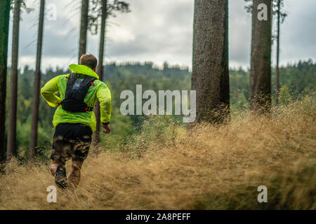 A young athlete in barefoot shoes runs up the mountain. Mountain run. Cross Country Running. Individual sports Stock Photo