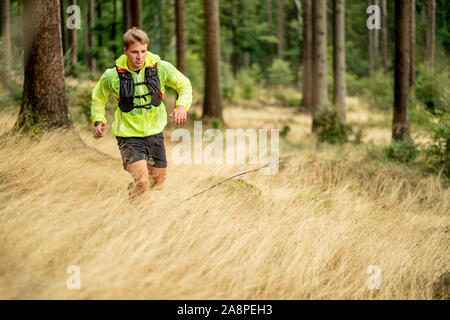 A young athlete in barefoot shoes runs up the mountain. Mountain run. Cross Country Running. Individual sports Stock Photo