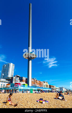 People sitting on the beach with the 162m tall observation tower Brighton i360 on the seafront, Brighton, UK Stock Photo