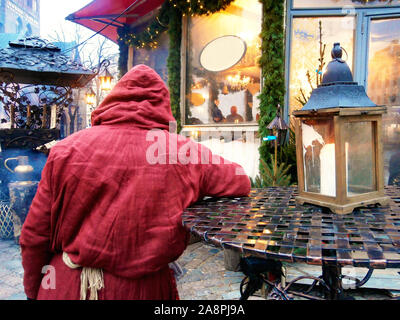 figure of a monk in the red robe in a town square on a Christmas holiday Stock Photo