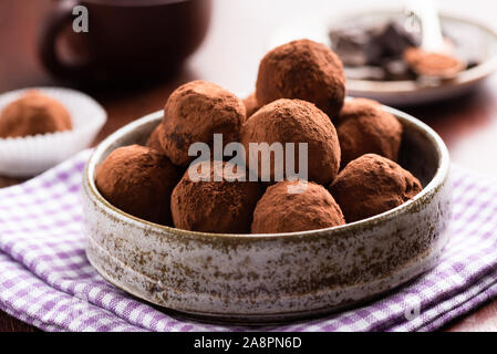 Chocolate truffles in ceramic dish on table. Homemade chocolate candy truffles Stock Photo