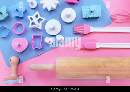 Top view flat lay with cute pink and blue baking utensils like wooden rolling pin, cookie cutters and stamps and baking mat Stock Photo