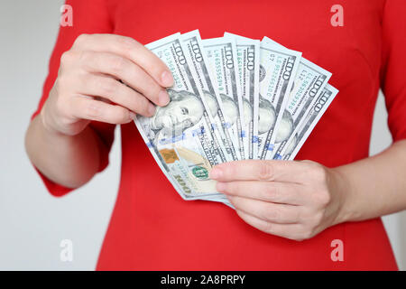 Woman in red dress holding US dollars in hands, close-up. Manager or businesswoman counts the money, concept of a salary, shopping, cash Stock Photo