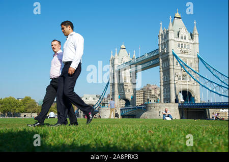 LONDON - OCTOBER 3, 2011: Pair of businessmen walk back from a lunch break at Potters Field Park, one of the few green spaces along the River Thames. Stock Photo