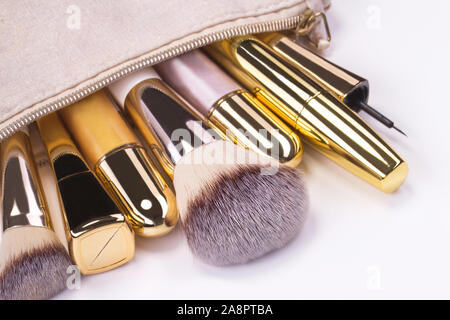 Set of brushes and cosmetic products in a cosmetic bag on a white background. Stock Photo