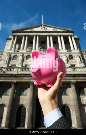Banker holding a bright pink piggy bank in old financial center of London, UK Stock Photo