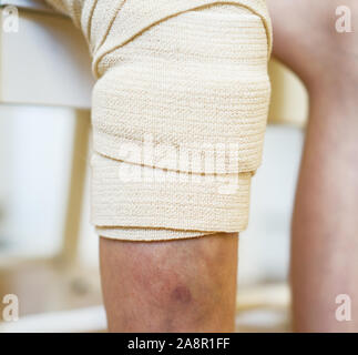 Child knee with gauze bandage. Close-up view. Stock Photo