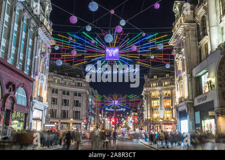 LONDON, UK - 11TH NOVEMBER 2018: Views along Oxford Street with colourful Christmas decorations and lights. Lots of people can be seen. Stock Photo