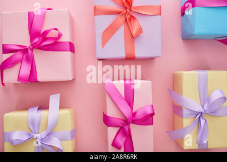 flat lay with colorful gift boxes with ribbons and bows scattered on pink background Stock Photo