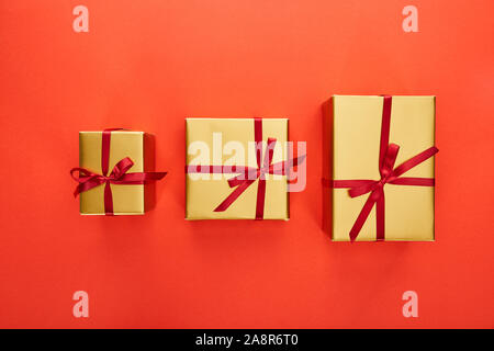 flat lay with three golden gift boxes on red background Stock Photo