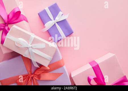 top view of colorful gift boxes with ribbons and bows scattered on pink background Stock Photo