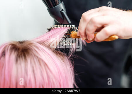 Hands Of Hairdresser Checks Short Pink Hair Of Girl On Gray