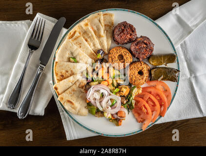 From above view of greek vegetarian sample with falafel, pita and dolmades takeout food plated at home with napkin Stock Photo