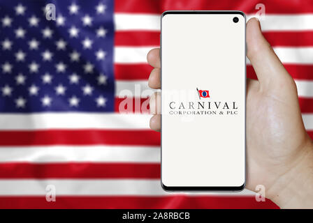 Logo of public company Carnival Corp. displayed on a smartphone. Flag of USA background. Credit: PIXDUCE Stock Photo