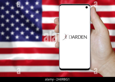 Logo of public company Darden Restaurants displayed on a smartphone. Flag of USA background. Credit: PIXDUCE Stock Photo