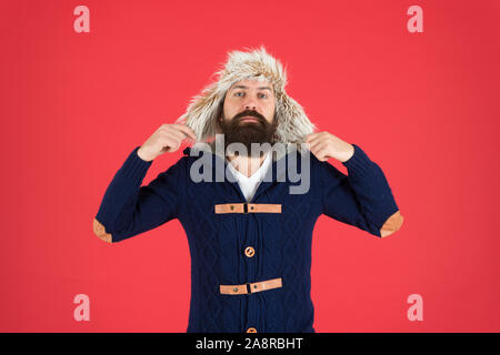 Man mature bearded stand warm jumper and hat on red background. Winter season menswear. Hipster rustic style outfit. Fashion menswear shop. Masculine clothes concept. Winter menswear. Clothes design. Stock Photo