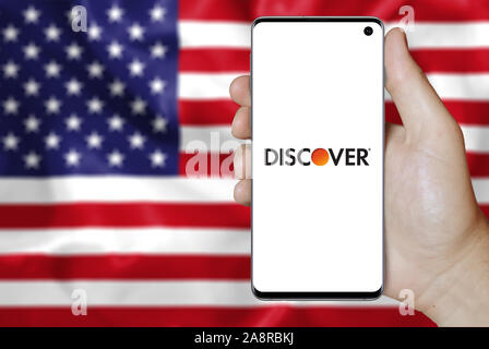 Logo of public company Discover Financial Services displayed on a smartphone. Flag of USA background. Credit: PIXDUCE Stock Photo