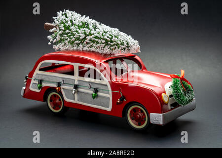 Little red vintage car carrying a Christmas tree on top Stock Photo