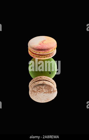 top view of three delicious colorful French macaroons of different flavors isolated on black Stock Photo