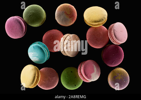 heap of delicious colorful French macaroons of different flavors isolated on black Stock Photo