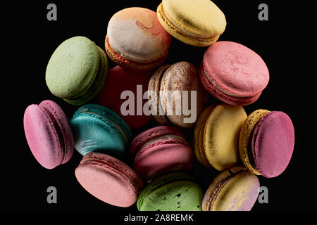 pile of delicious colorful French macaroons of different flavors isolated on black Stock Photo