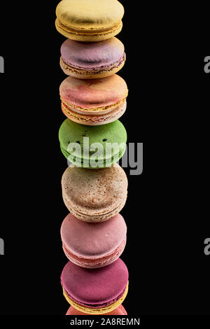 row of delicious colorful French macaroons of different flavors isolated on black Stock Photo