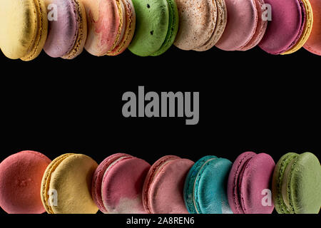 rows of delicious colorful French macaroons of different flavors isolated on black with copy space Stock Photo