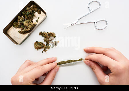 cropped view of woman rolling joint near marijuana buds in box and scissors Stock Photo