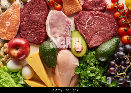 Top view of assorted raw meat, poultry, fish, eggs, vegetables, fruits, nuts, greenery and cheese Stock Photo