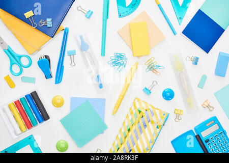 Top view of blue and yellow scattered school supplies with notepads, pencil case and calculator isolated on white Stock Photo