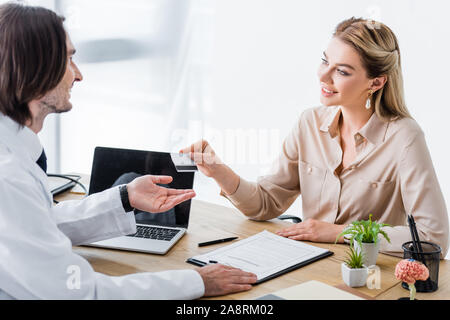 beautiful and happy patient giving credit card to doctor Stock Photo