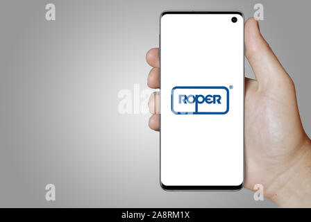 Logo of public company Roper Technologies displayed on a smartphone. Grey background. Credit: PIXDUCE Stock Photo