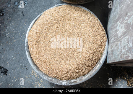 Nha Trang, Vietnam - March 11, 2019: Dai Diem Nam neighborhood. Closeup of metal basin filled to the top with beige-brown rice chaff. Stock Photo