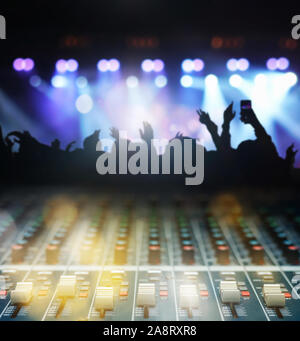 Closeup up hands the sound mixer over the photo blurred of Concert crowd in silhouettes of Music fanclub follow up the songer at the front of stage wi Stock Photo
