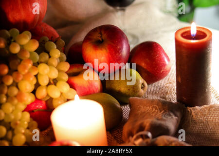 White grapes sultana red apples and green pears with candles autumn fruits and vegetables still life on a sackcloth Stock Photo