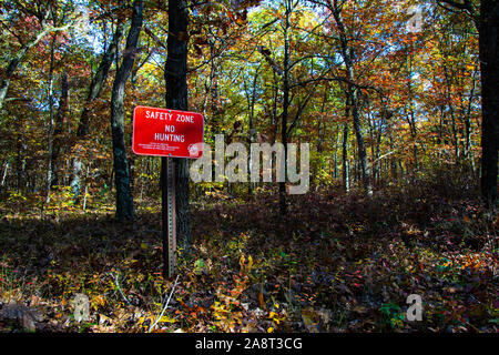 A 'Safety Zone - No Hunting' sign at the Winamac State Fish and Wildlife Area in Winamac, Indiana, with colorful autumn leaves in the background Stock Photo