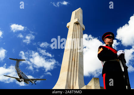 Beijing, Malta. 10th Nov, 2019. A soldier stands guard in front of the War Memorial as a military aircraft flies over in Floriana, Malta, on Nov. 10, 2019. Malta marked Remembrance Day to salute the war dead on Sunday. Credit: Jonathan Borg/Xinhua/Alamy Live News Stock Photo