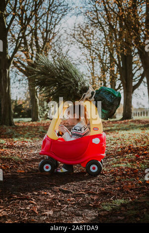 Child driving toy car with christmas tree on top Stock Photo