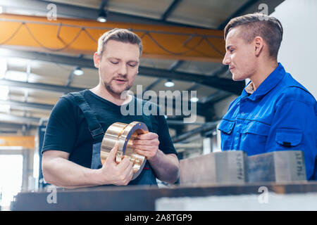 Master discussing a workpiece with his apprentice or trainee Stock Photo
