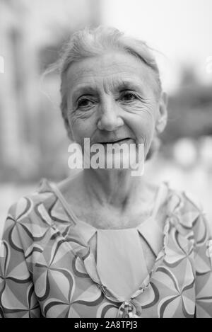 Beautiful senior tourist woman relaxing around the city in black and white Stock Photo