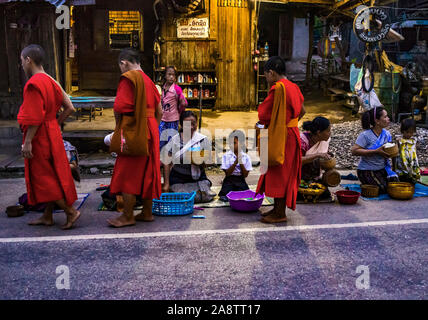 Monks in Saffron Robes in the streets at dawn in the World Heritage Listed town Luang Prabang in Laos in the morning alms giving ceremony or Tak Bak Stock Photo
