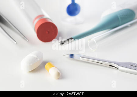 Pills with surgical scalpel and forceps, glass tubes and stool test sampler isolated on white background. Laboratory, antibiotics, medicine, pharmacy Stock Photo