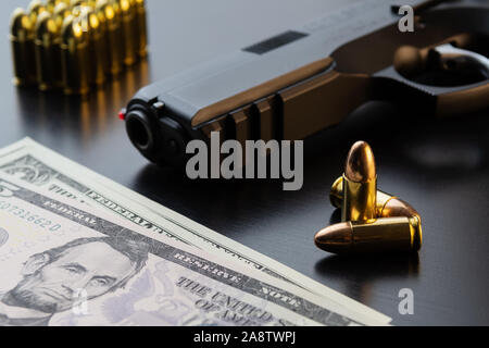 9 mm semi-automatic pistol, full metal jacket bullets and dollar banknotes on black background. Conceptual mockup of gun control and crime. Stock Photo