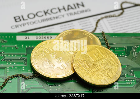 Closeup of golden Bitcoin and Ethereum cryptocurrency coins with chain on printed circuit board and mockup blockchain transactions list page Stock Photo