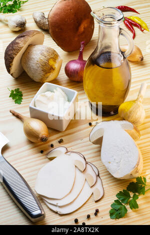 Sliced penny bun for mushroom carpaccio on table laden with spices, olive oil, garlic, onions and mushrooms. Cep, porcino, boletus edulis Stock Photo