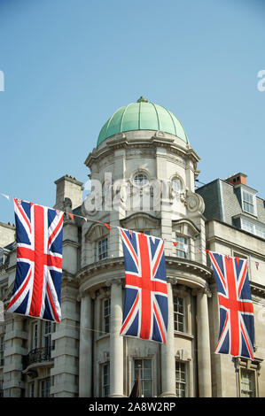 British Union Jack flag decorations strung above the streets of London, UK under sunny blue sky Stock Photo