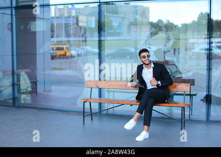 Man in suit arabic puts on sunglasses with tablet near business center Stock Photo